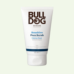 A 125 ml white tube of Sensitive Face Scrub for men, with quinoa seed and natural origin ingredients, brown and blue text, stands upright on a light background. Made from recycled material for sensitive skin.