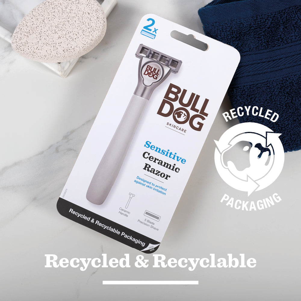 A Sensitive Ceramic Razor in recycled packaging rests on a white surface with a pumice stone and navy towel. Text reads “Recycled & Recyclable,” emphasizing the razor’s eco-friendly packaging.