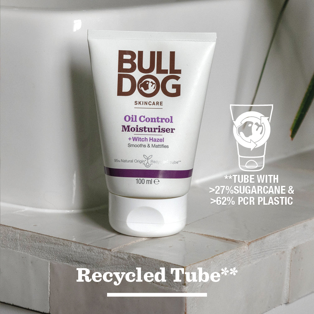 A tube of Oil Control Moisturiser, designed for oily skin, rests on a bathroom surface. It contains witch hazel and natural-origin ingredients in packaging made from 27% sugarcane and 62% PCR plastic. Recycled Tube**.