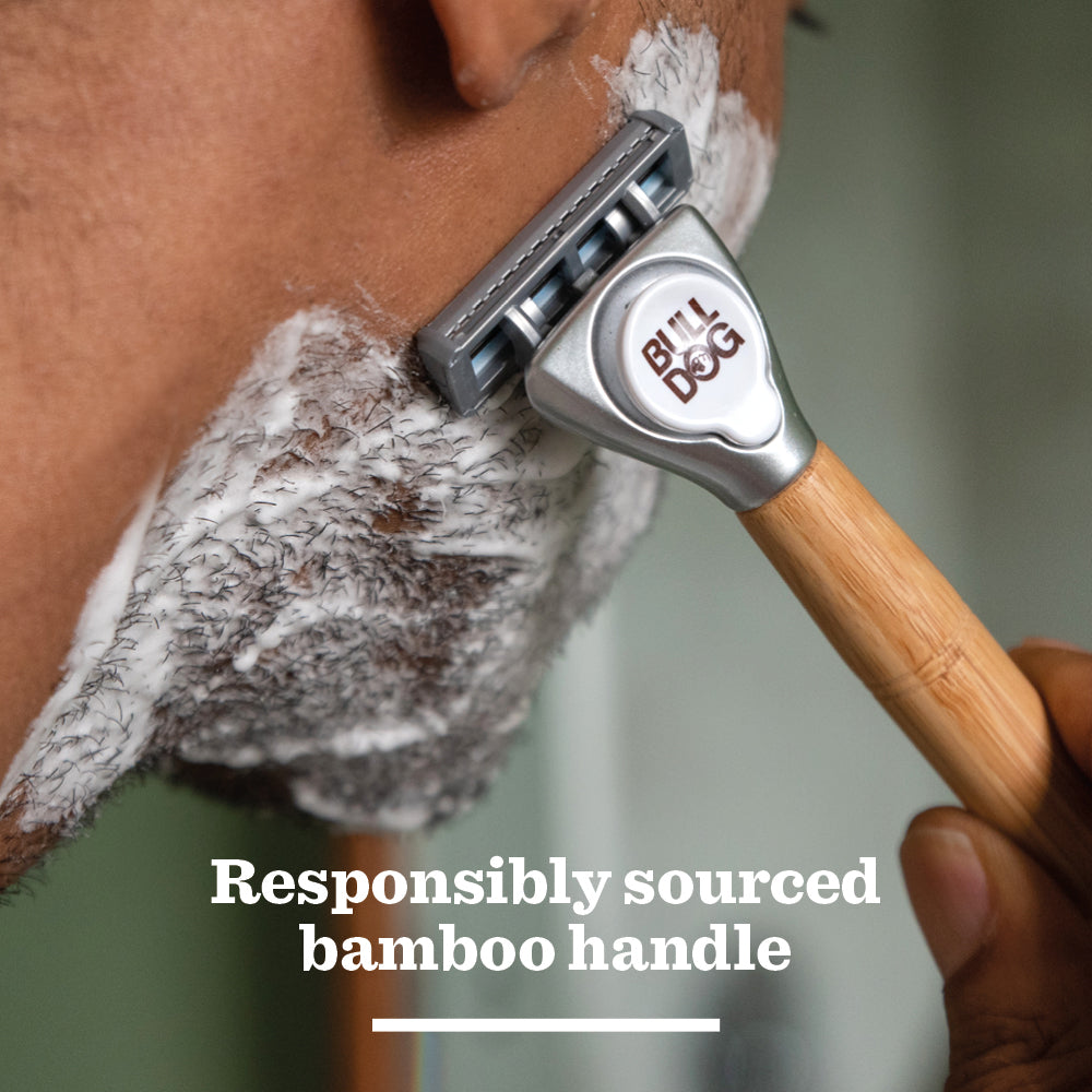 A close-up of a person shaving with a razor featuring a bamboo handle and Original Steel Blades. Shaving cream covers their skin, and text reads: Responsibly sourced bamboo handle.