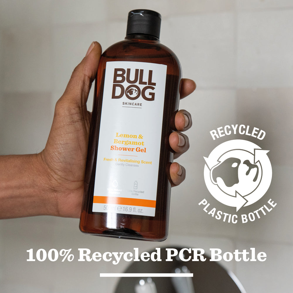 A hand holds a bottle of Lemon & Bergamot Shower Gel made with natural fragrance. The label notes it uses recycled plastic. Text below states: 100% Recycled PCR Bottle—ideal for mens skincare routines.