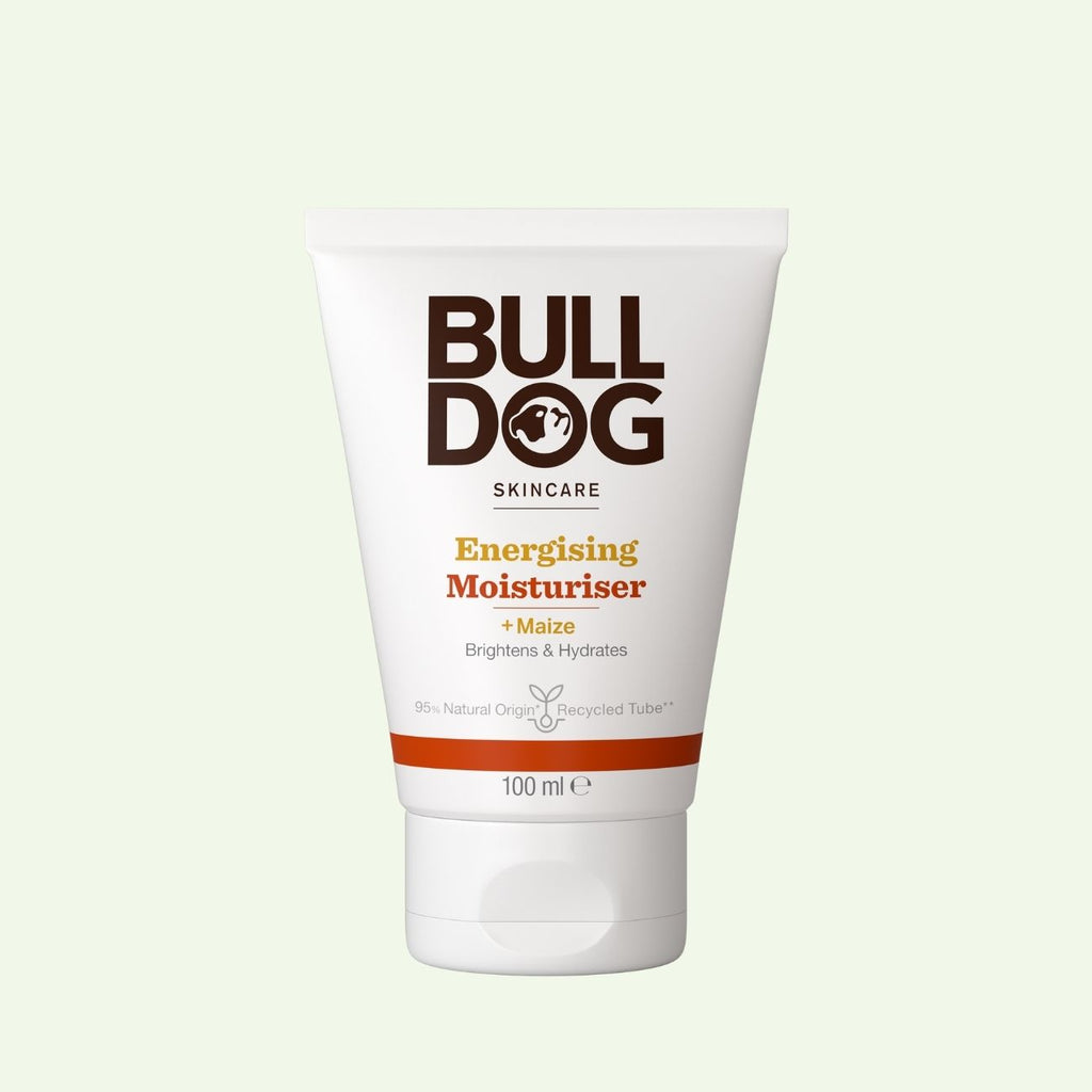 A white 100ml tube of Energising Moisturiser for men with maize, featuring brown and orange text. Designed to brighten and hydrate skin with natural origin ingredients. Shown against a light green background.