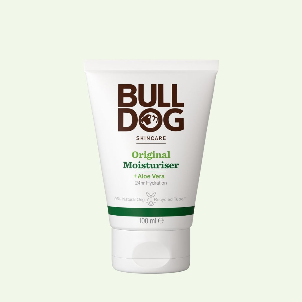 A 100 ml white tube of Bulldog Skincare Original Moisturiser for men with Aloe Vera, offering 24-hour hydration and made with natural origin ingredients, is displayed against a light green background.